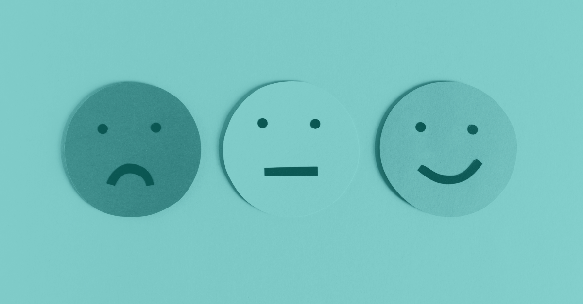 Three paper smiley faces in a row displaying different emotions – sad, neutral, and happy – on a teal background